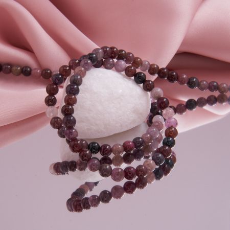 Nahaufnahme einer hochwertigen, glatt geschliffenen Multicolor-Spinellkette mit Edelsteinen in Rosa, Rot, Grau und Schwarz.